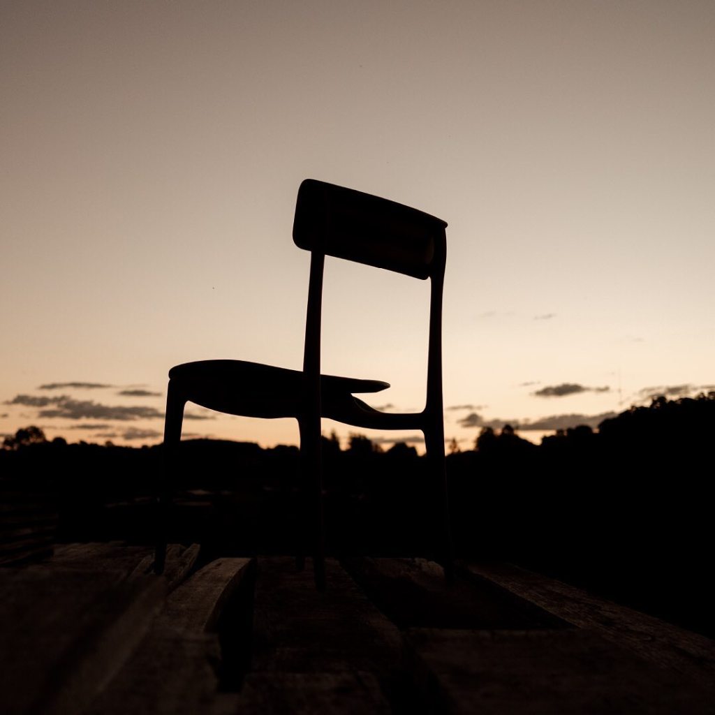 Chaise en bois élégante fabriquée en bois dur brésilien certifié, photographiée devant des planches de bois empilées dans un atelier de meubles.