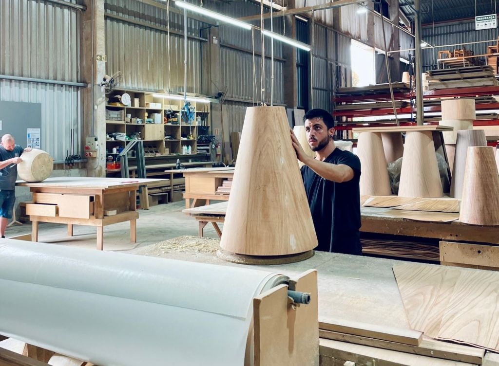 Brazilian furniture manufacturing workshop with craftsman shaping solid wood furniture components